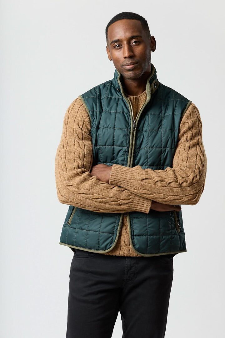 Veste sans manches matelassée avec détails en velours côtelé portée avec un pull marron, style élégant et pratique.