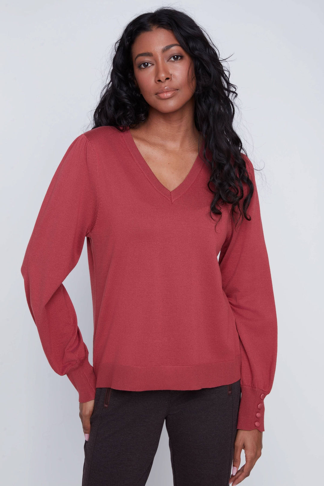 Chandail encolure en V, manches bouffantes, coupe droite, style chic, porté avec pantalon ajusté.