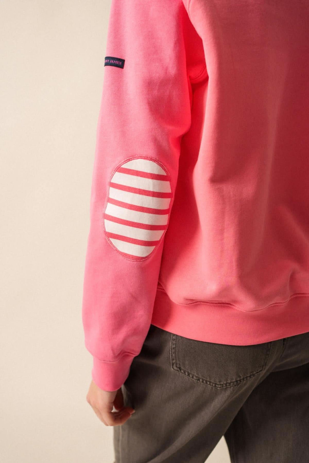 Sweat rose avec coudières rayées sur manches, col rond et style décontracté, idéal pour un look casual.