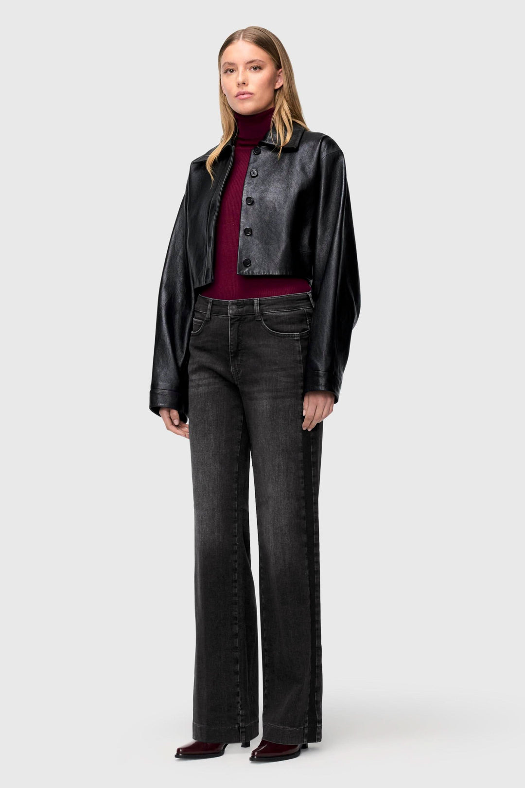 Femme en jeans à jambe large délavés, top ajusté et veste en cuir, style tendance et décontracté.