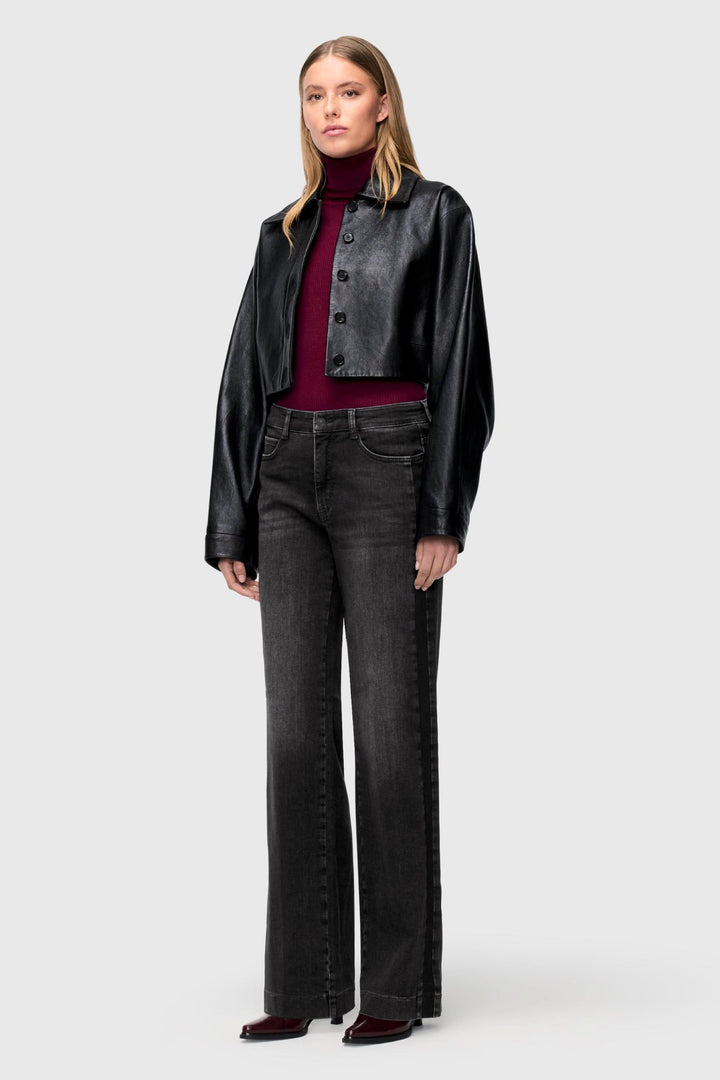 Femme en jeans à jambe large délavés, top ajusté et veste en cuir, style tendance et décontracté.