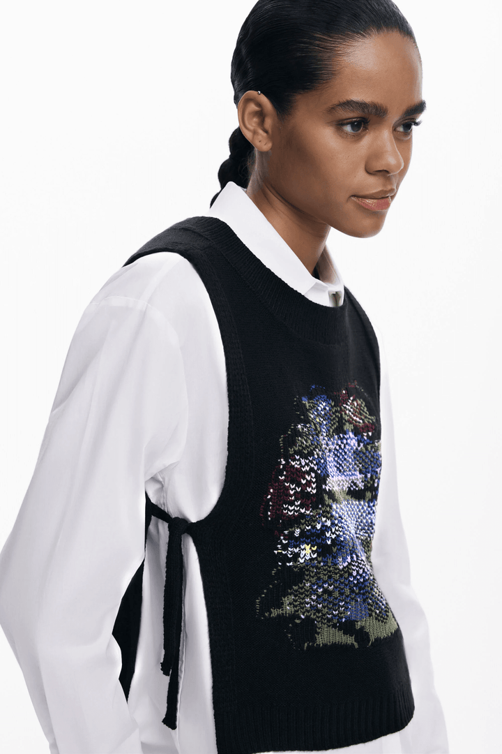 Femme portant Chemise 2 en 1 avec chandail sans manches noir brodé et chemise blanche, style moderne et élégant.