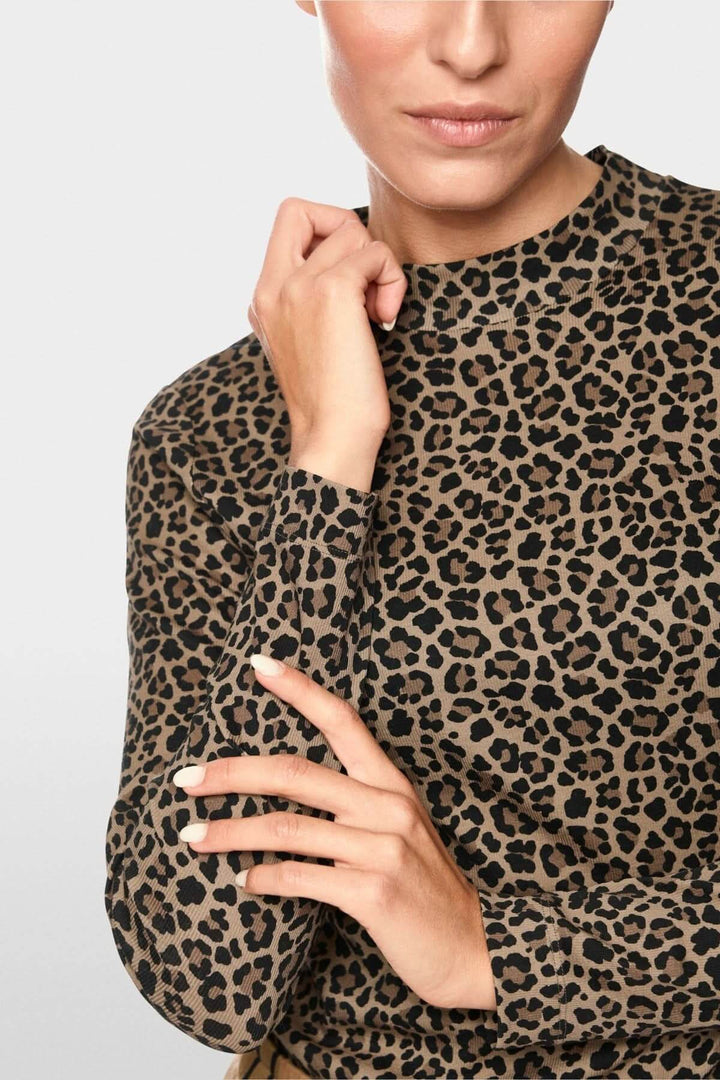 Femme portant un chandail imprimé léopard ajusté avec col montant et manches longues, soulignant la silhouette par son motif audacieux.
