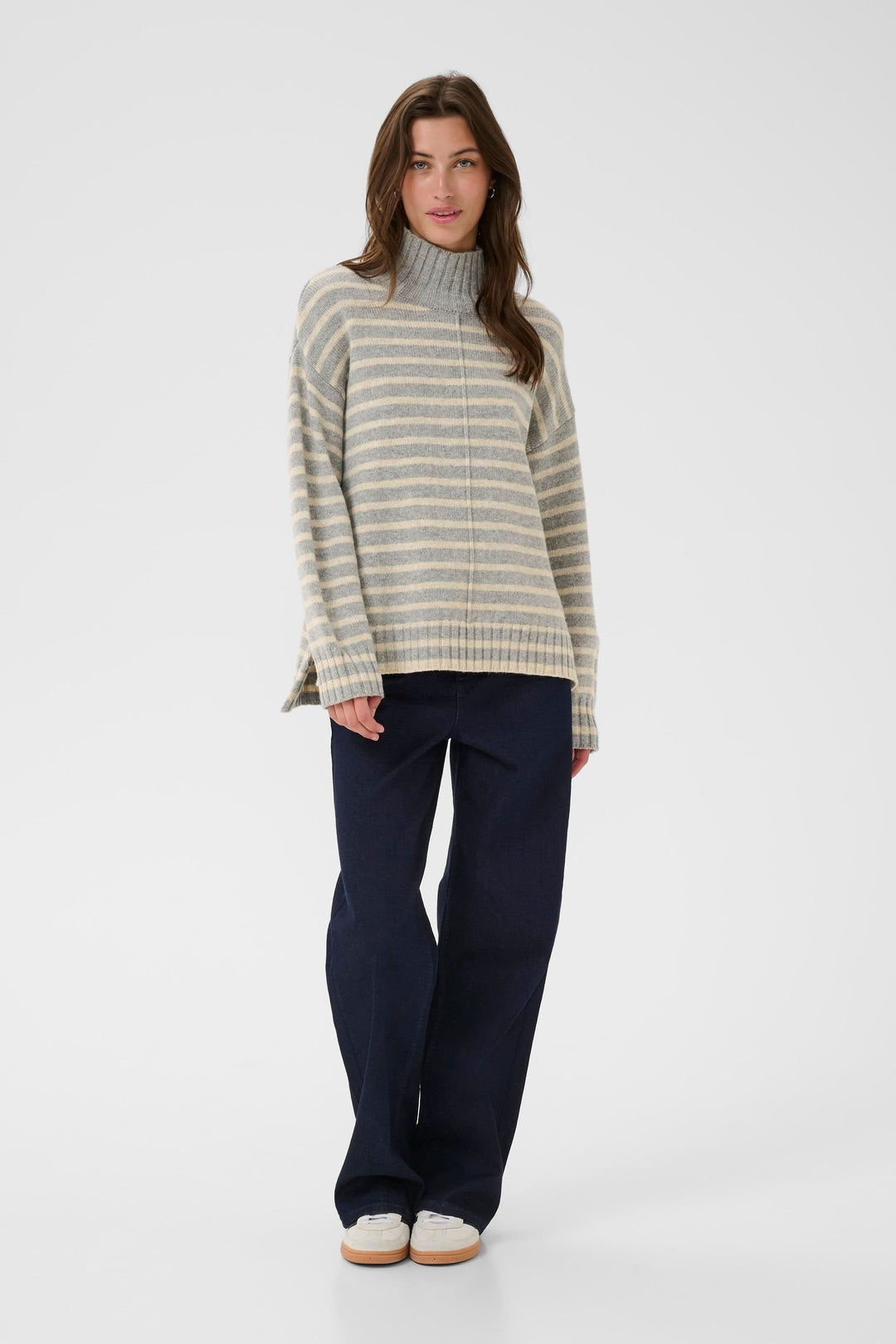 Tricot à col montant avec rayures horizontales, coupe ample, porté avec un jean foncé pour un look décontracté et élégant.