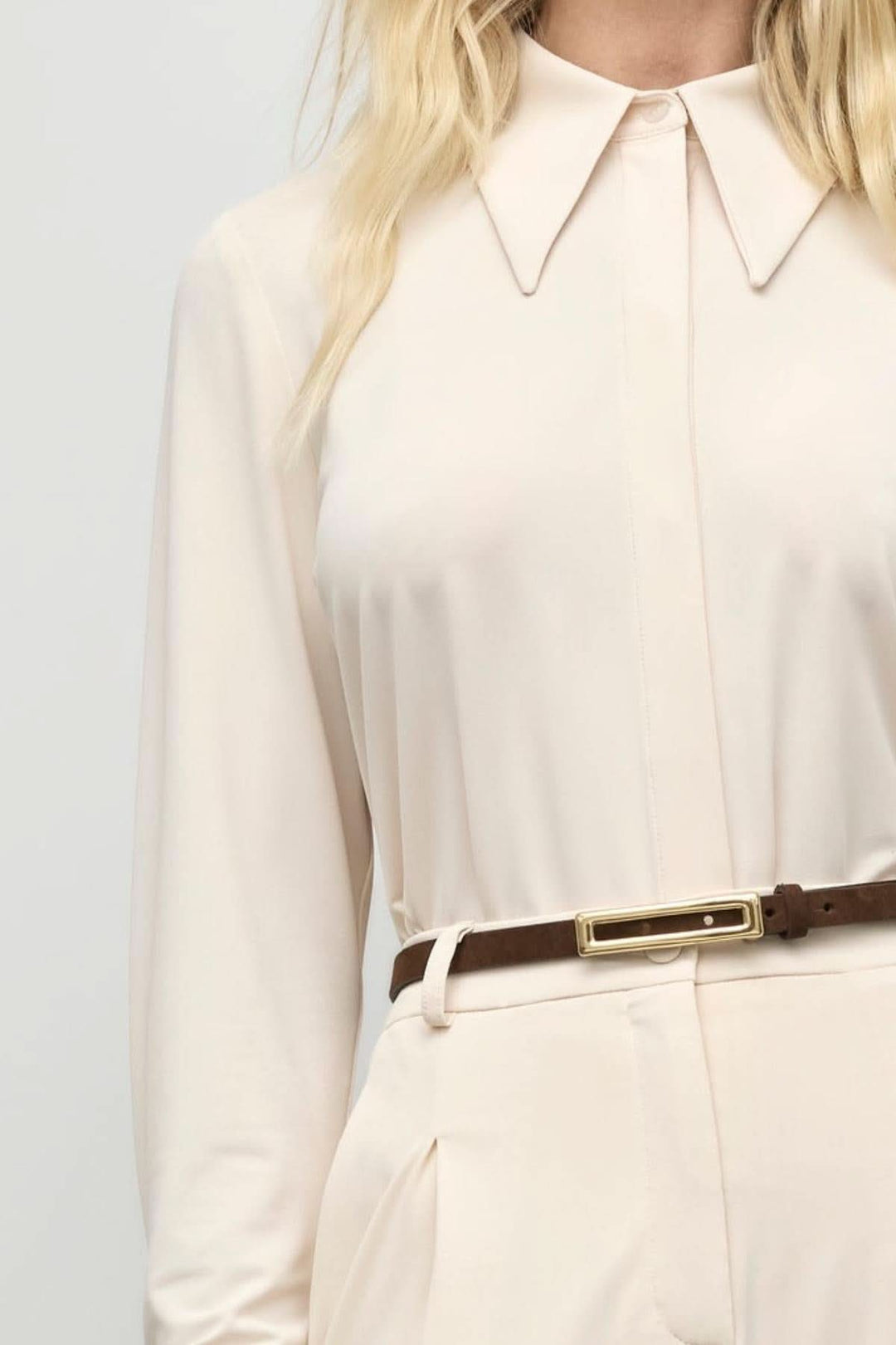 Chemisier en jersey mat beige avec col prononcé et ceinture, conçu pour une coupe fluide et moderne.