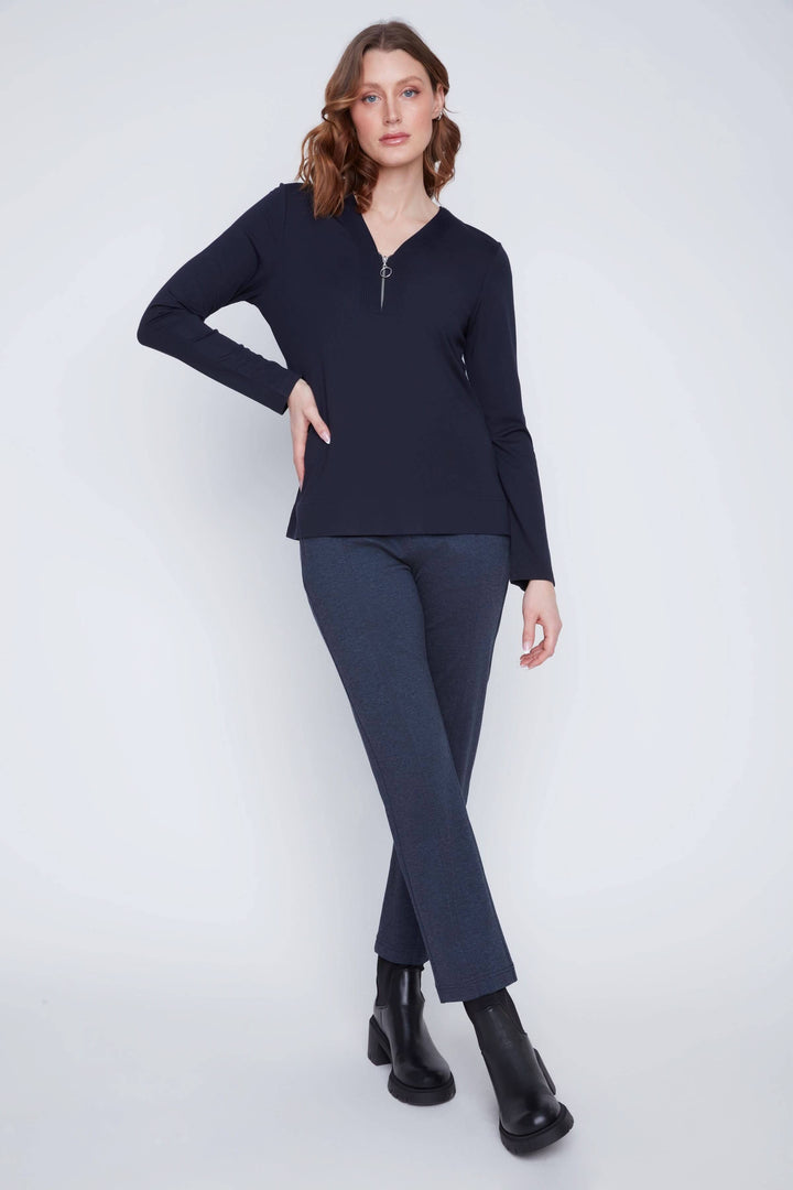 Chandail encolure en V zippée, manches longues, style décontracté, porté avec pantalon ajusté.