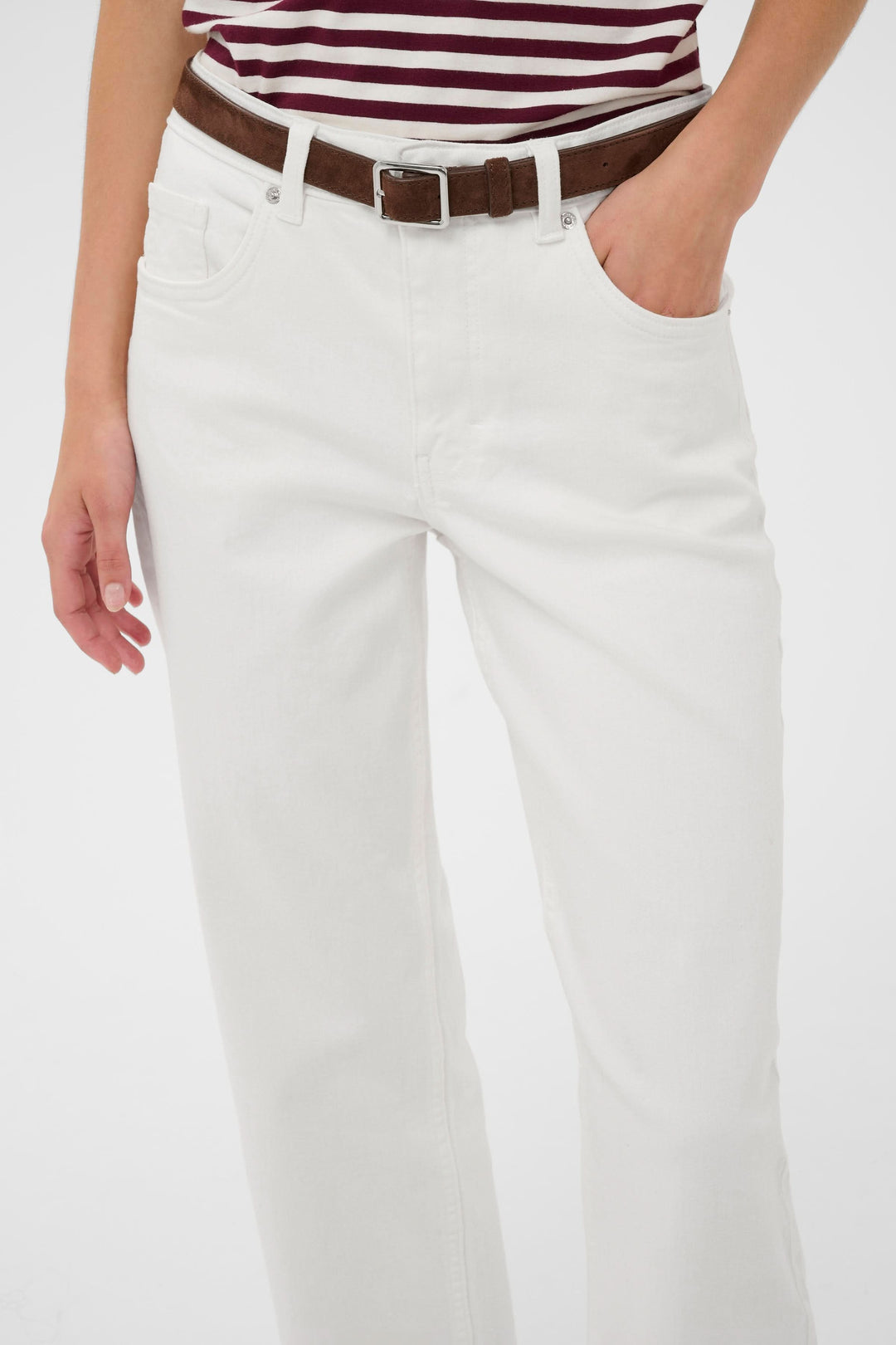 Femme portant Jeans Judyas coupe droite longueur cheville, couleur blanc, avec ceinture en cuir marron, style casual et épuré.