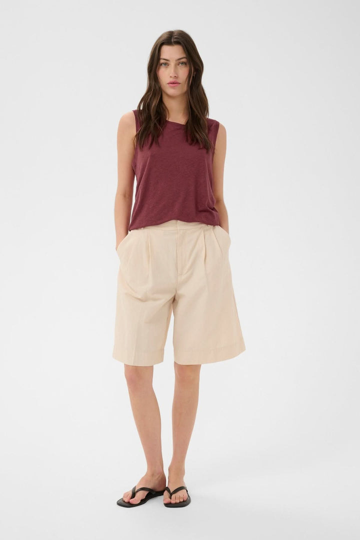 Femme portant la Cami fluide Buena, top sans manches avec encolure ronde, coupe droite et fluide, idéal pour un look polyvalent.