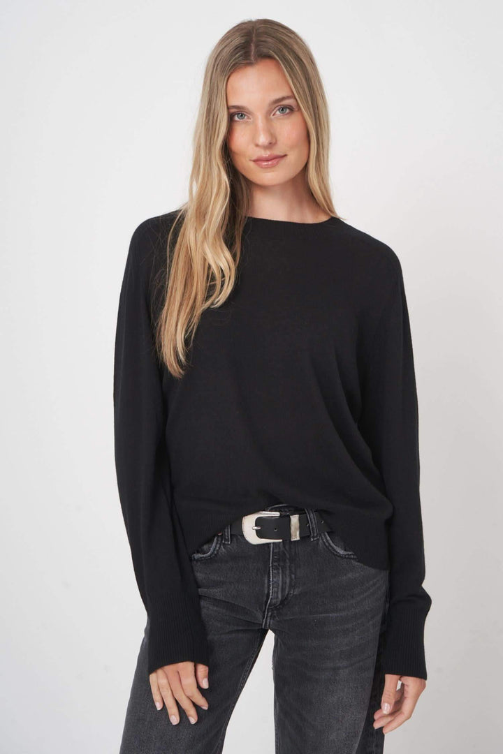 Chandail en laine noir avec coupe droite, porté avec un jean, pour un look décontracté et élégant.