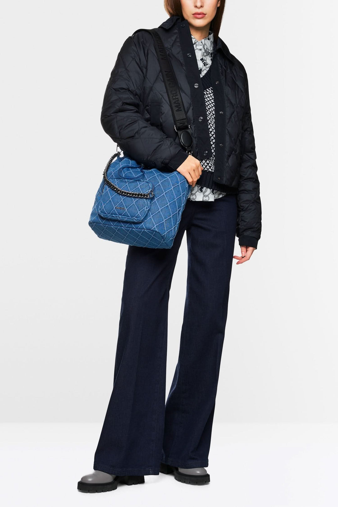 Femme portant une veste matelassée noire avec un sac en jean et un pantalon fluide, style moderne et écoresponsable.