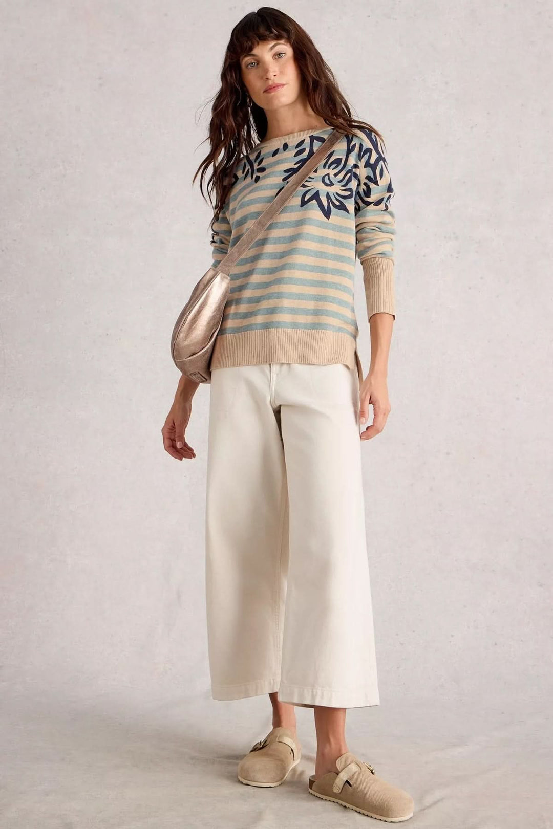 Chandail imprimé avec motifs contrastants, porté avec un pantalon claire et sac, style moderne et graphique.