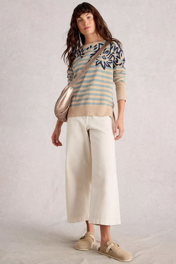 Chandail imprimé avec motifs contrastants, porté avec un pantalon claire et sac, style moderne et graphique.