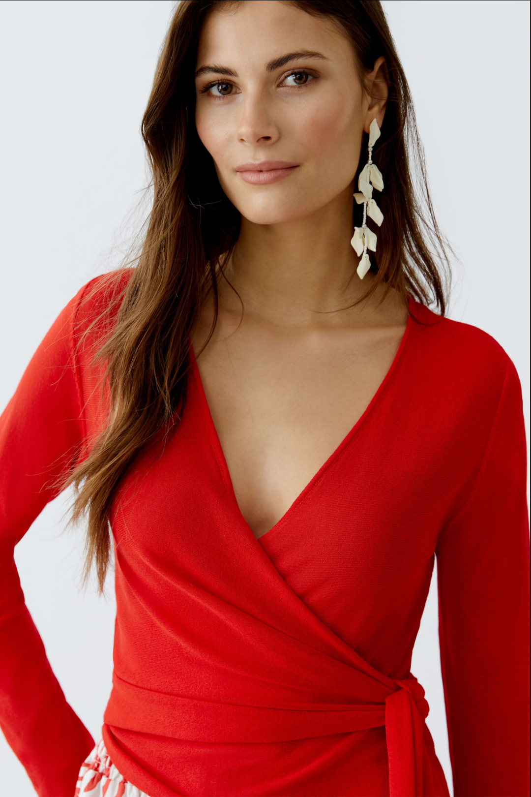 Décolleté en V d'un chandail portefeuille rouge, ajusté avec des manches longues, mettant en valeur une silhouette féminine.