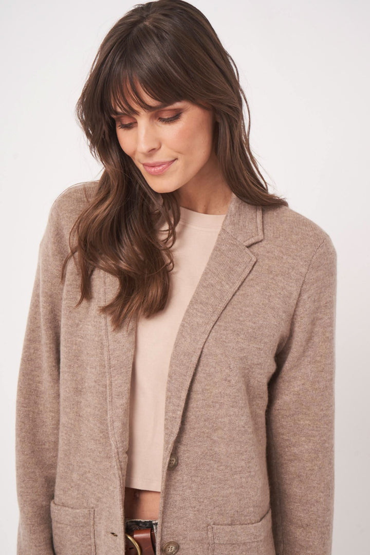 Femme portant un veston en maille beige, mélange de laine et cachemire, style moderne et élégant.