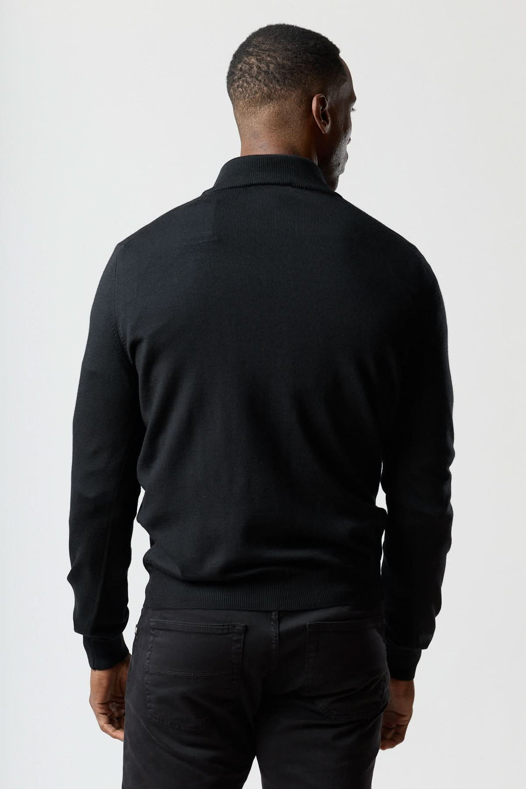 Homme portant un chandail à demi-zip en laine mérinos noir, vue arrière, élégance italienne et moderne.