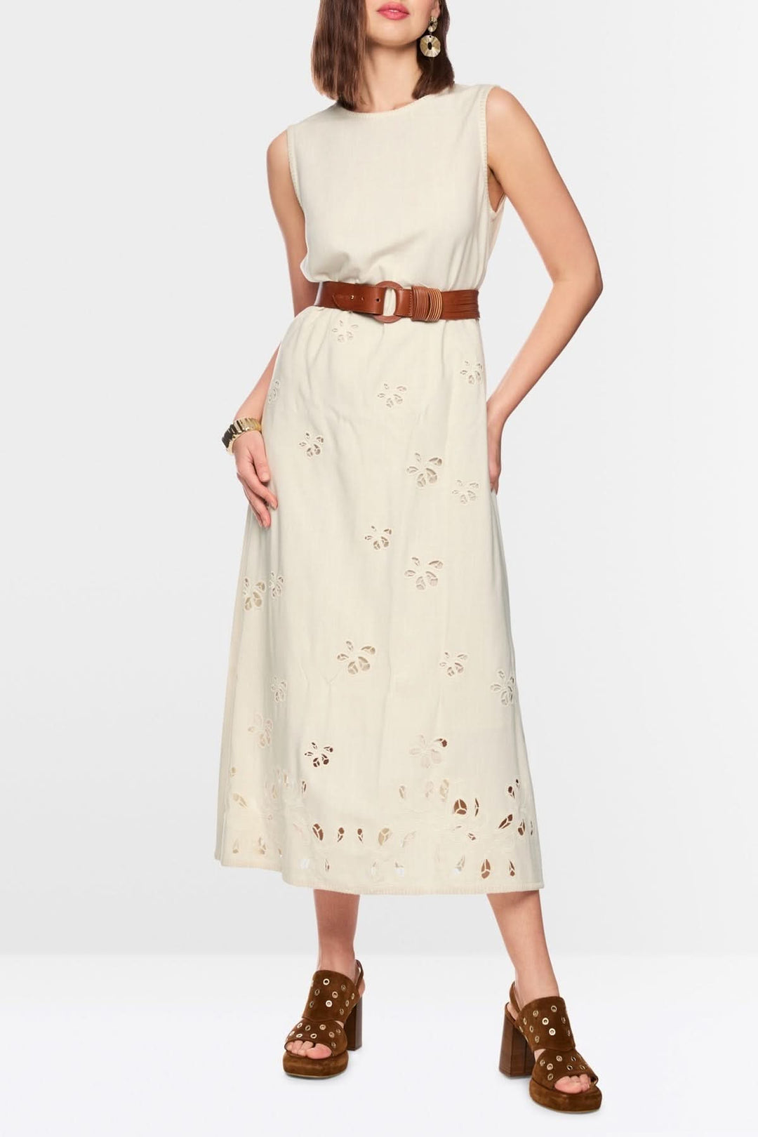 Robe longue fluide à broderies délicates avec ceinture en cuir portée par une femme élégante, coupe droite et sans manches.