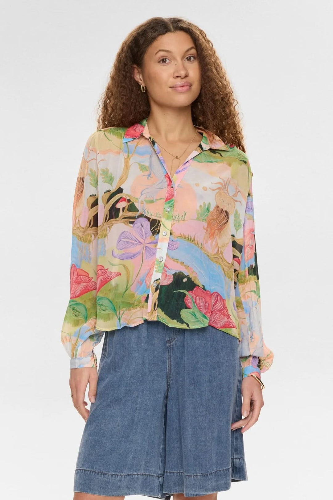 Chemise fluide imprimée à manches longues avec motifs artistiques, portée par une femme, style élégant et confortable.