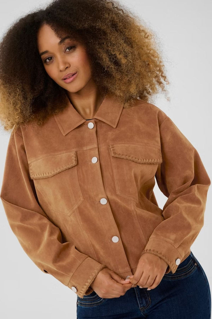 Femme portant une veste en suédine de style western, avec poches et boutons-pression, devant un fond neutre.