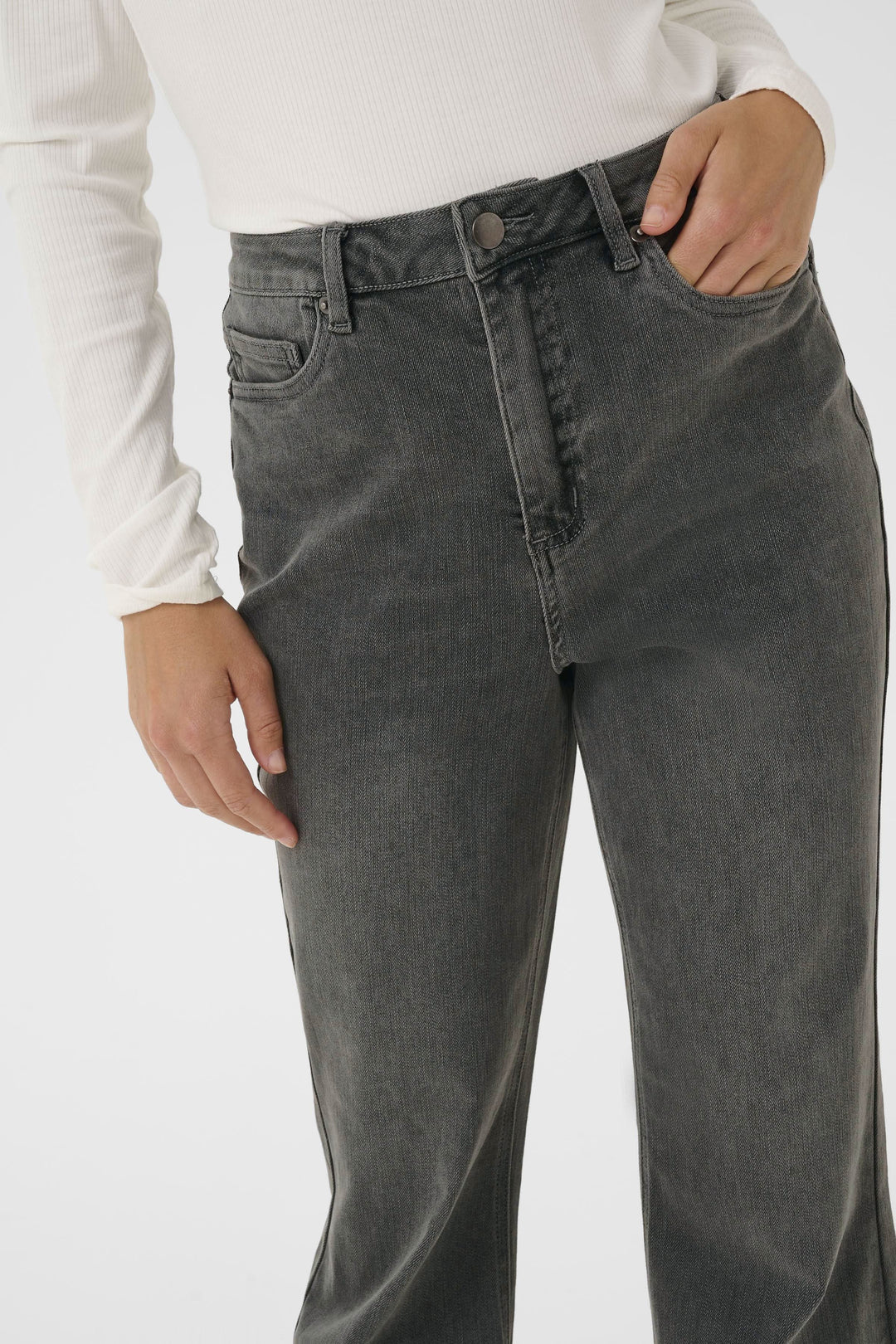 Jean à jambe évasée, taille haute, finition délavée, style rétro, porté avec un chandail ajusté.