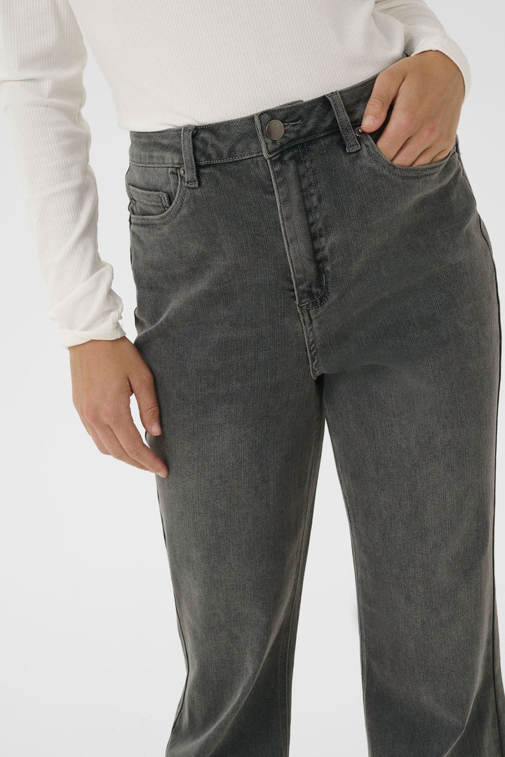 Jean à jambe évasée, taille haute, finition délavée, style rétro, porté avec un chandail ajusté.