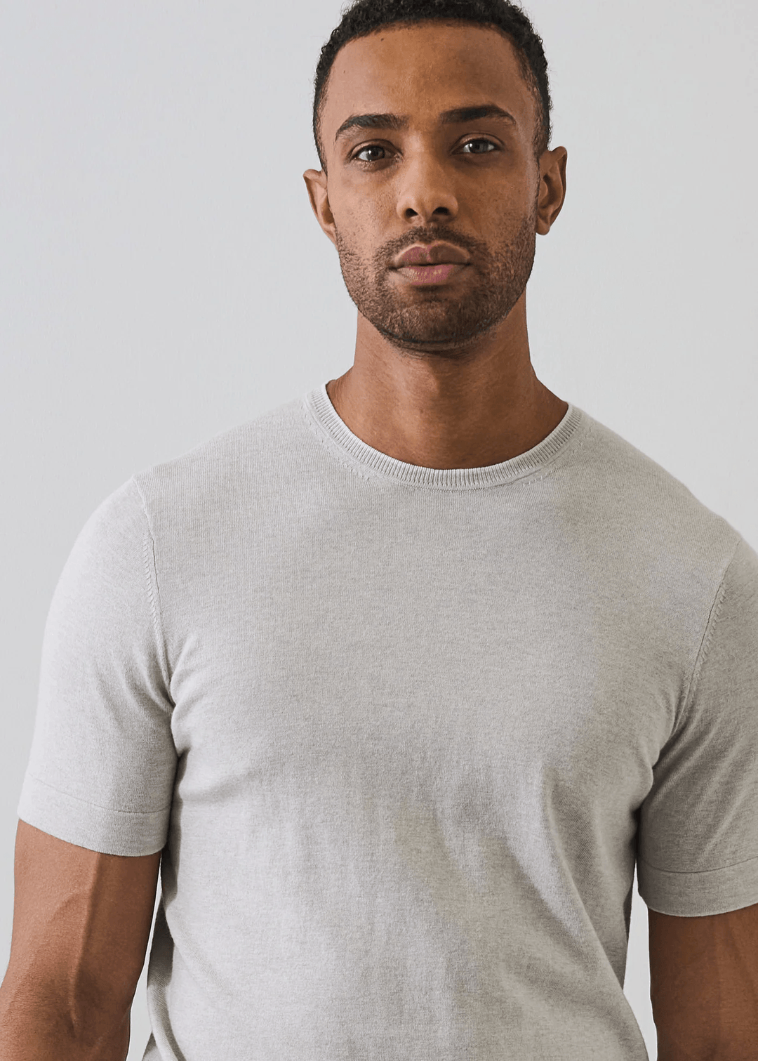 Homme portant un t-shirt en coton et cachemire gris clair avec un design épuré et détails subtils au col.