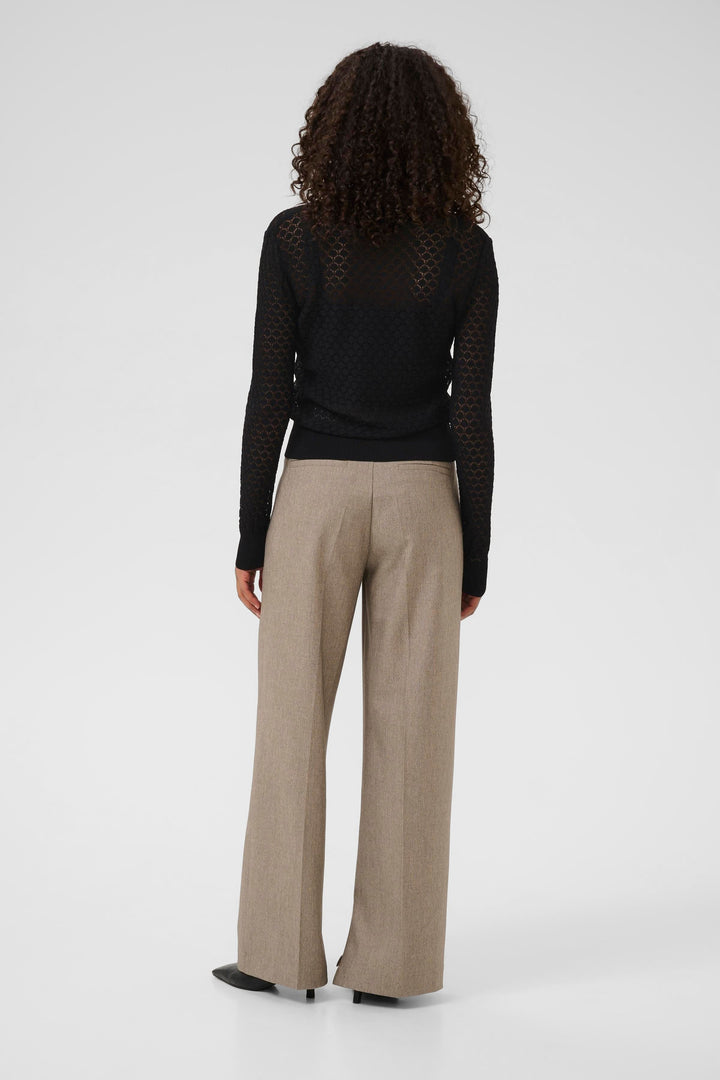 Chandail Raiko en maille ajourée noir, vu de dos, associé à un pantalon beige, style élégant et sophistiqué.