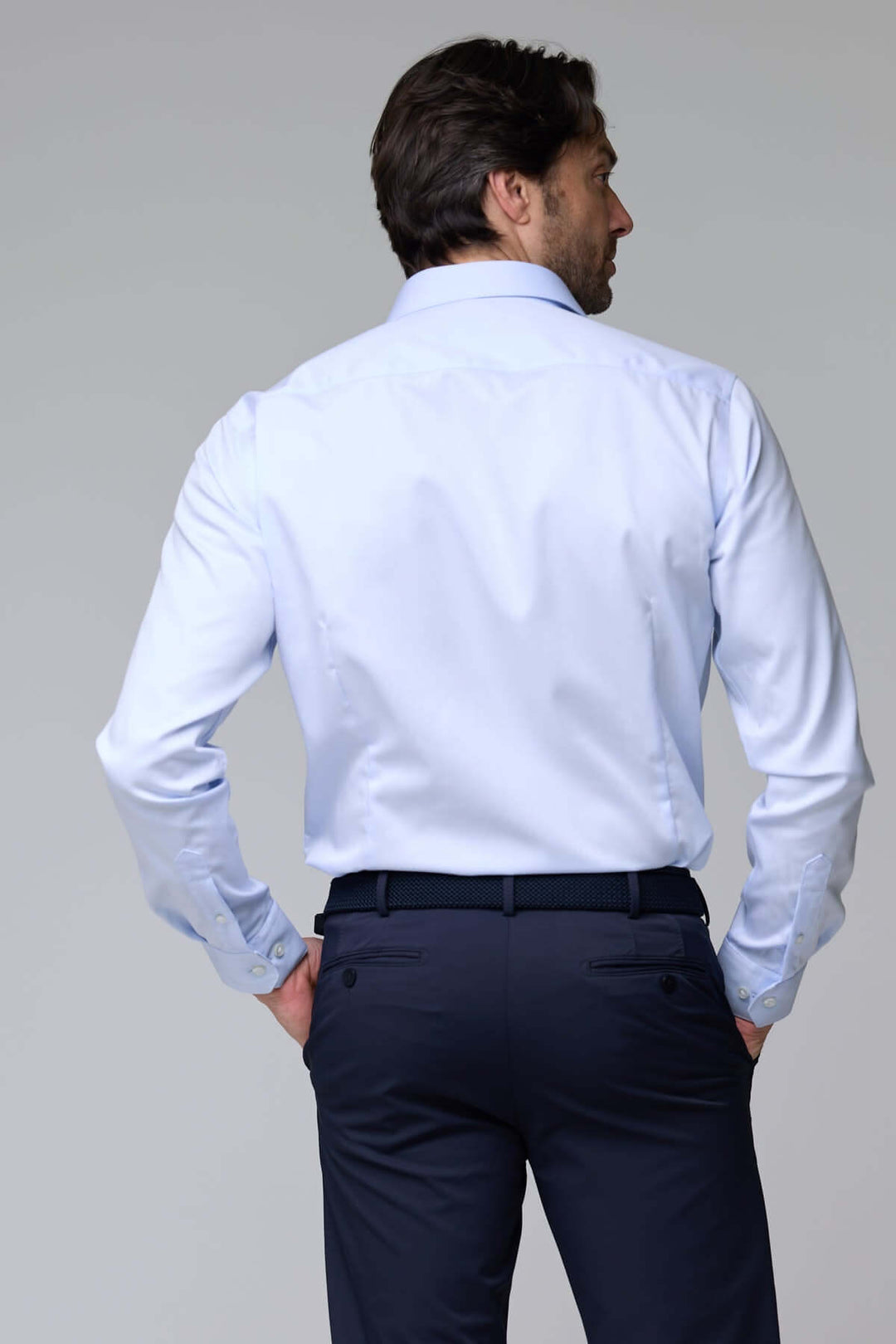 Homme vêtu de chemise habillée satinée à manches longues, vue de dos, montrant la texture lisse et l'éclat discret de la chemise.