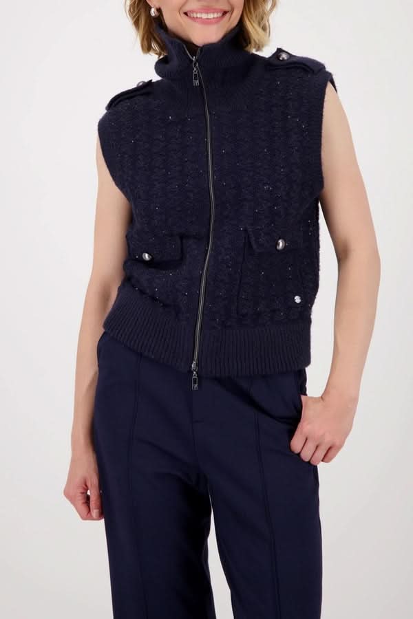 Veste sans manches zippée en maille texturée avec col montant et poches à rabat, portée pour un look moderne et élégant.
