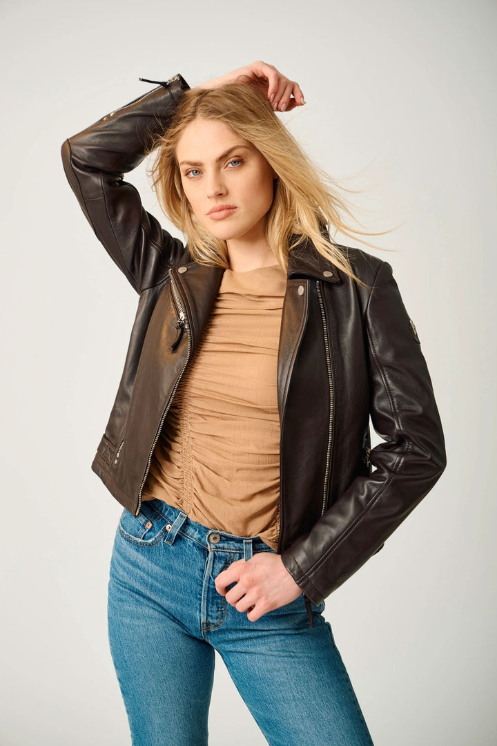 Femme portant le Manteau Pasja en cuir style perfecto avec fermeture éclair asymétrique et col à revers, look casual-chic.