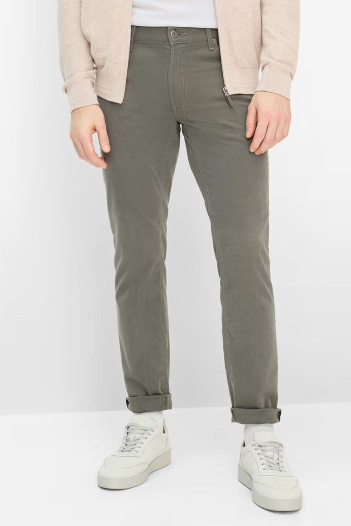 Pantalon ajusté longueur cheville en kaki, confortable et moderne, avec poches latérales, porté avec des chaussures blanches.