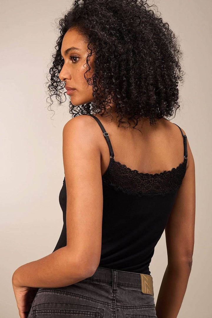 Femme portant une camisole noire avec dentelle, fines bretelles et coupe ajustée, vue de dos.