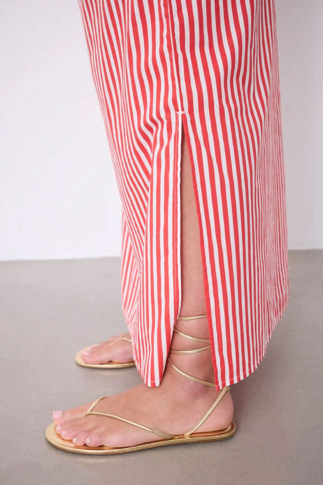 Jupe Ilona longue rayée taille élastique avec motif rayé vertical, fente latérale et sandales dorées, offrant une silhouette fluide.