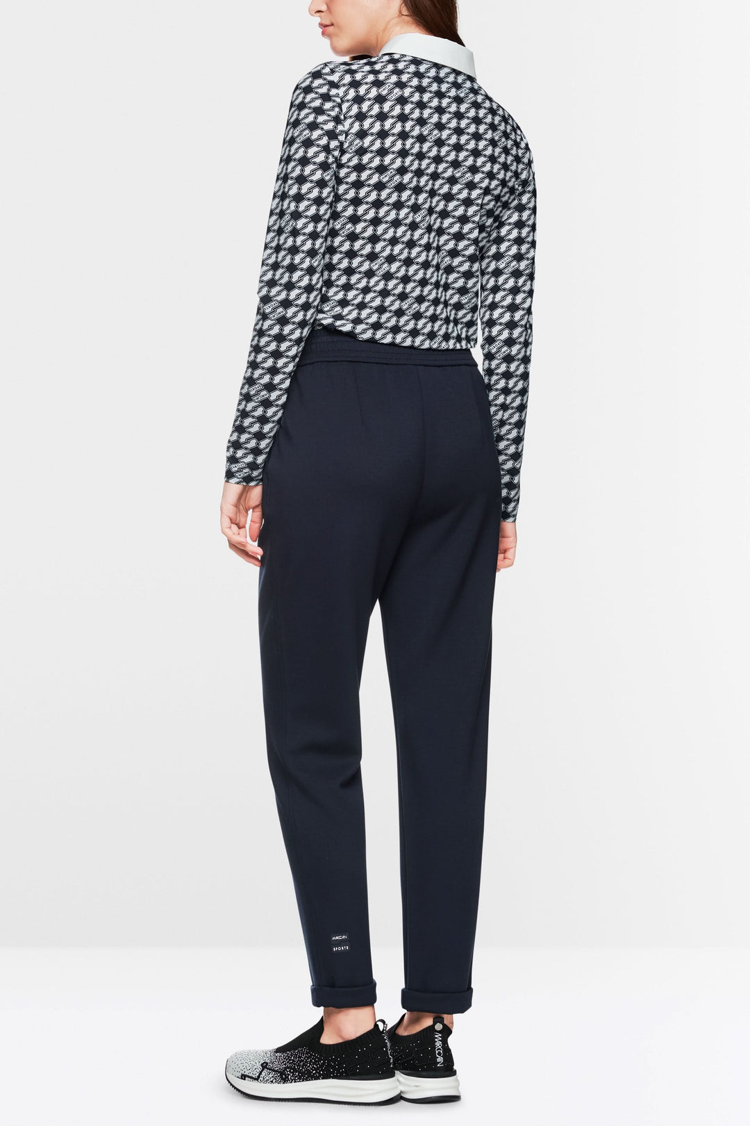 Femme de dos portant un pantalon jogger noir à taille haute et un haut à motifs modernes.