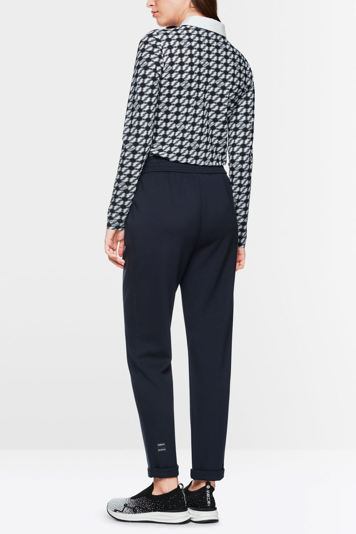 Femme de dos portant un pantalon jogger noir à taille haute et un haut à motifs modernes.