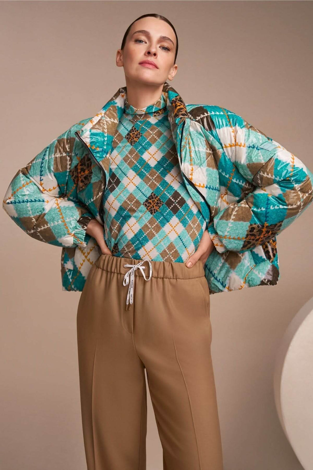 Femme portant un chandail à manches longues au motif argyle multicolore et col montant, style contemporain chic et élégant.