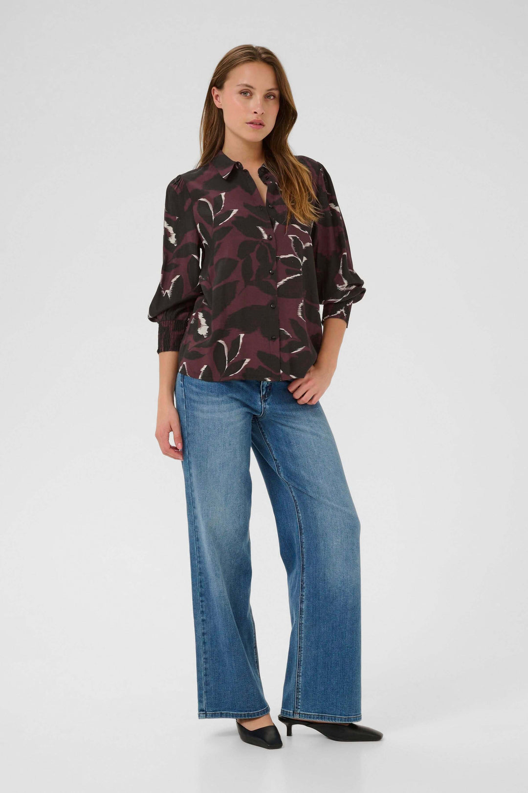 Femme portant Chemise Mille imprimée à manches longues et poignets smockés, look moderne avec jean flair.