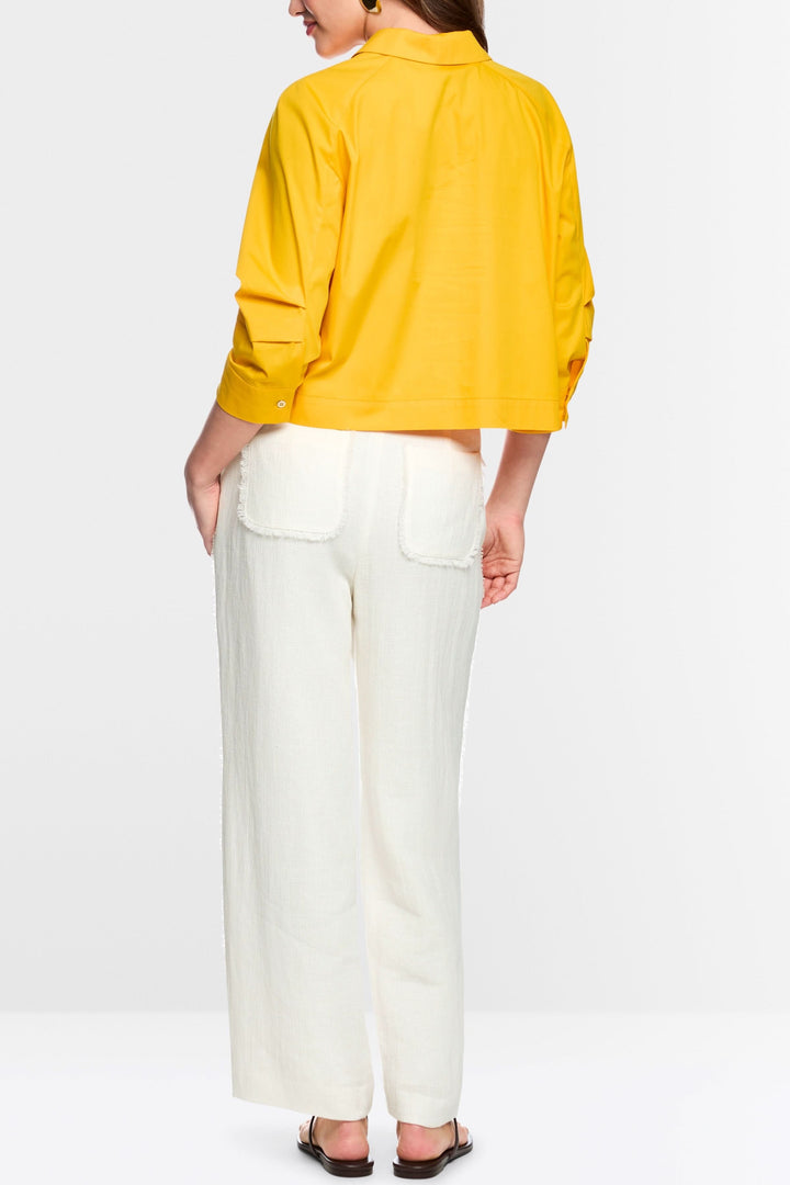 Femme portant un Pantalon WUKARI large texturé blanc avec une chemise jaune, vue de dos, style épuré et élégant.