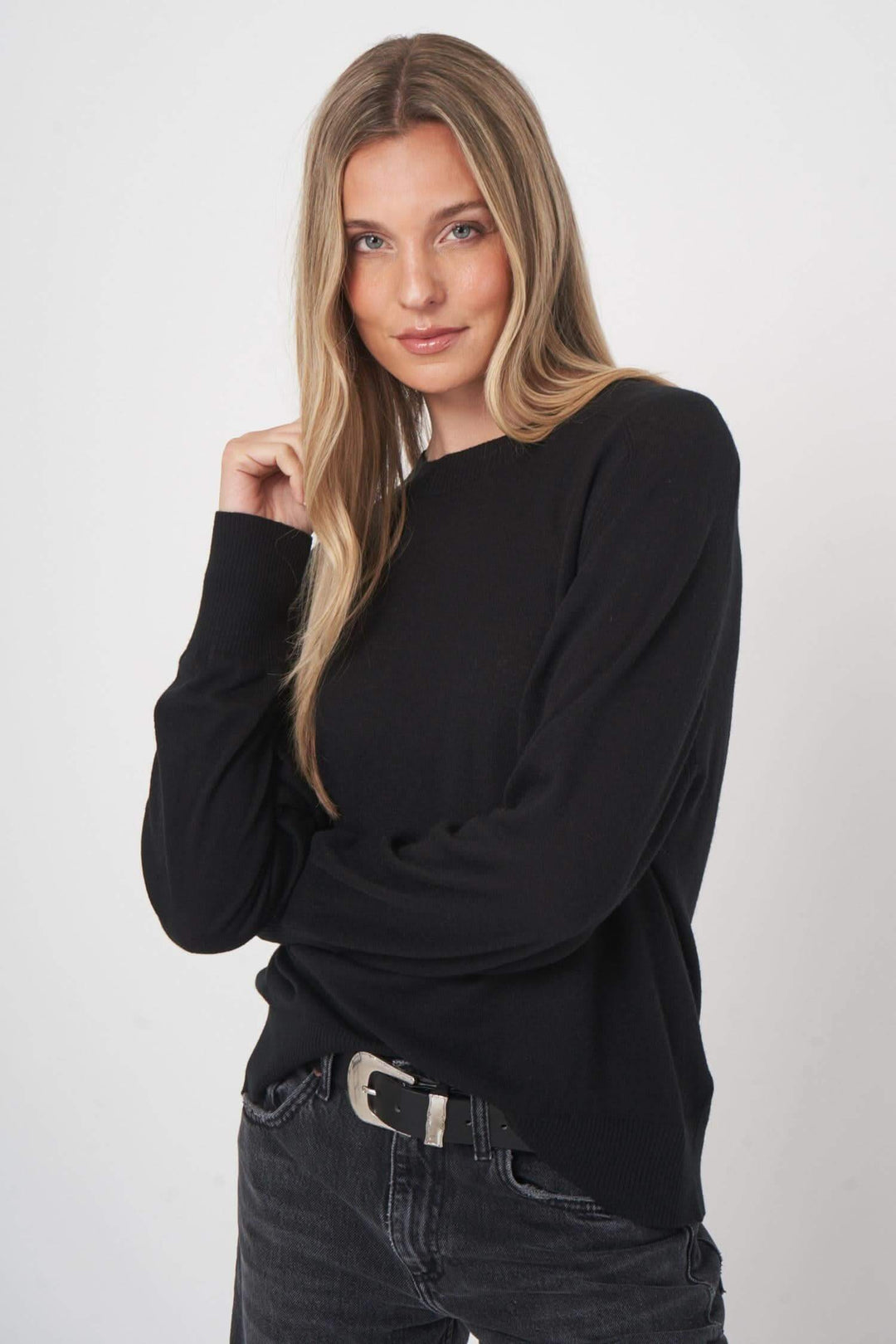 Chandail en laine noir avec coupe droite et finitions côtelées, porté par une femme souriante.