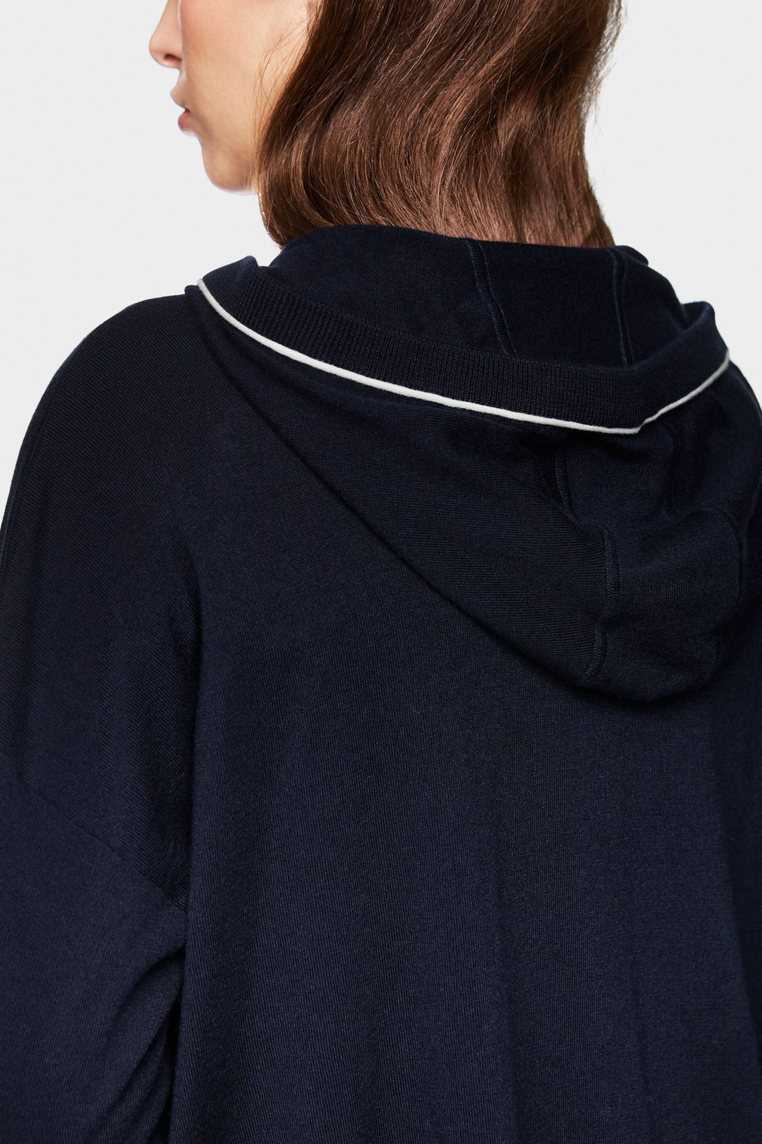 Détail du dos d'un cardigan tricoté avec capuchon et bord contrastant, offrant un style décontracté.