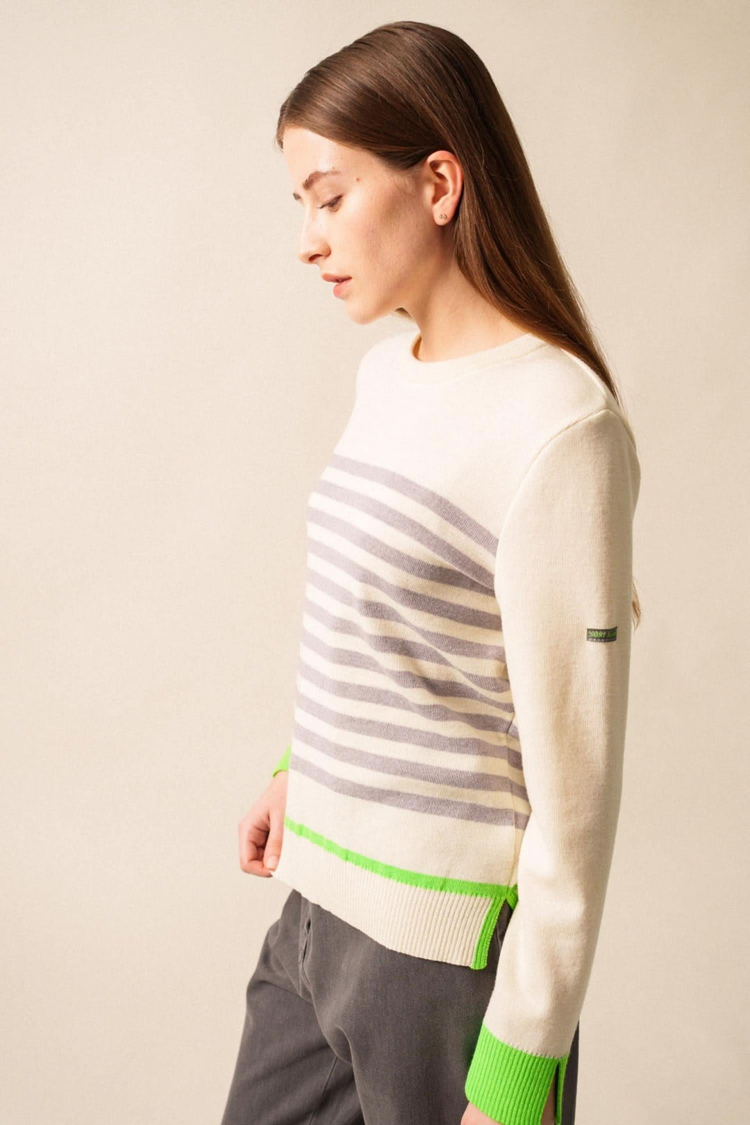 Chandail Evian rayé contemporain avec finitions fluo, porté avec un jean gris, style décontracté et moderne.