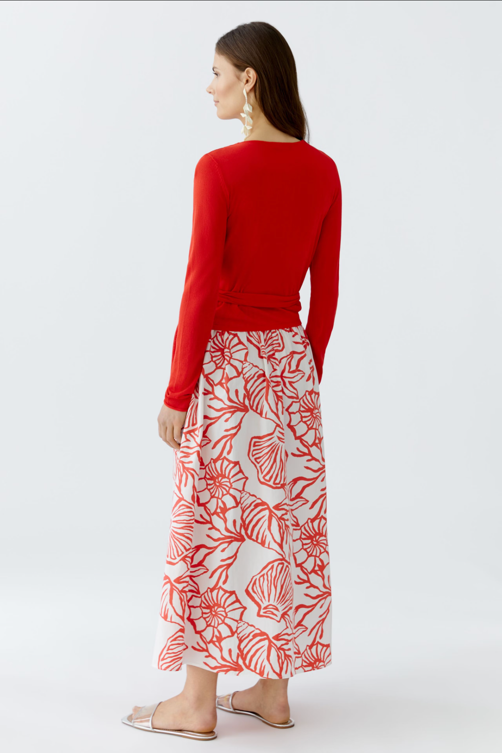 Haut cache-cœur rouge à manches longues, porté avec une jupe imprimée. Vue arrière, style élégant et féminin.