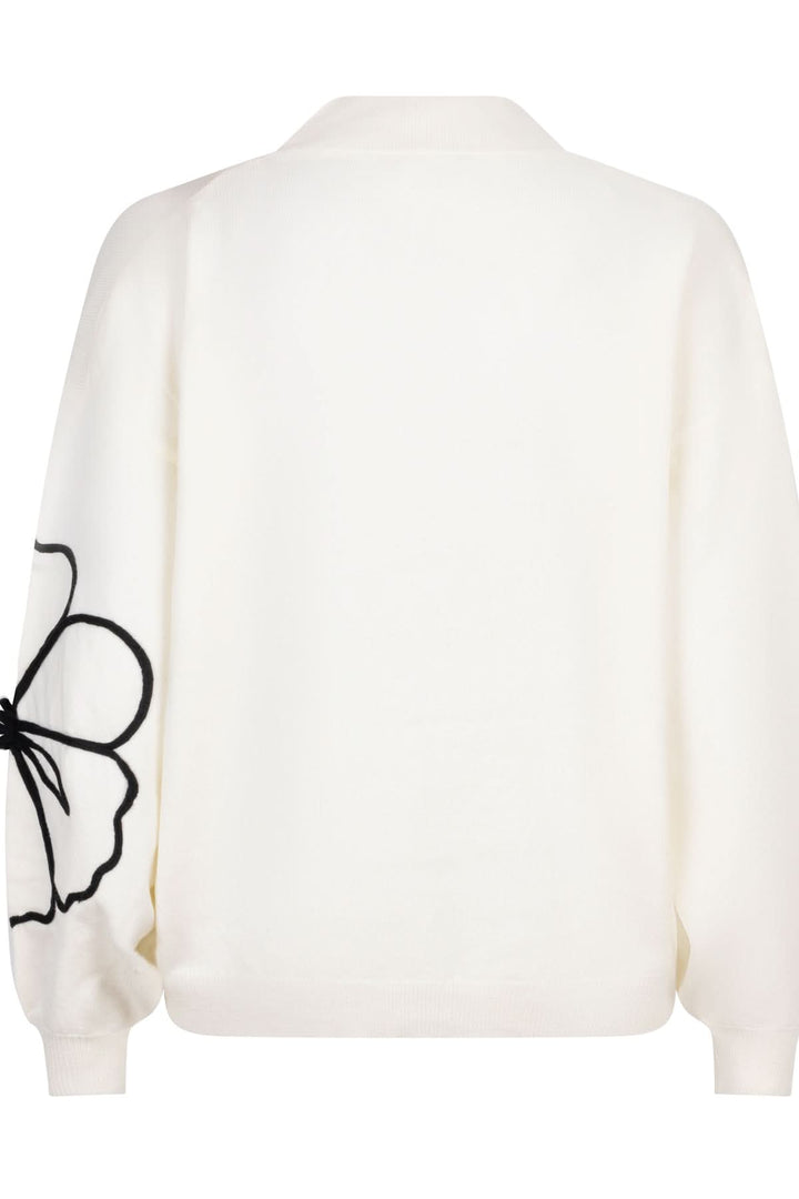 Chandail en maille blanc avec grande fleur brodée noire à l'arrière pour un style élégant et décontracté.
