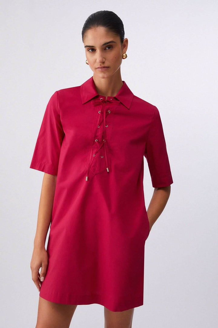 Femme portant une robe droite à col chemise lacé rouge avec manches courtes, encolure distinctive, coupe épurée.