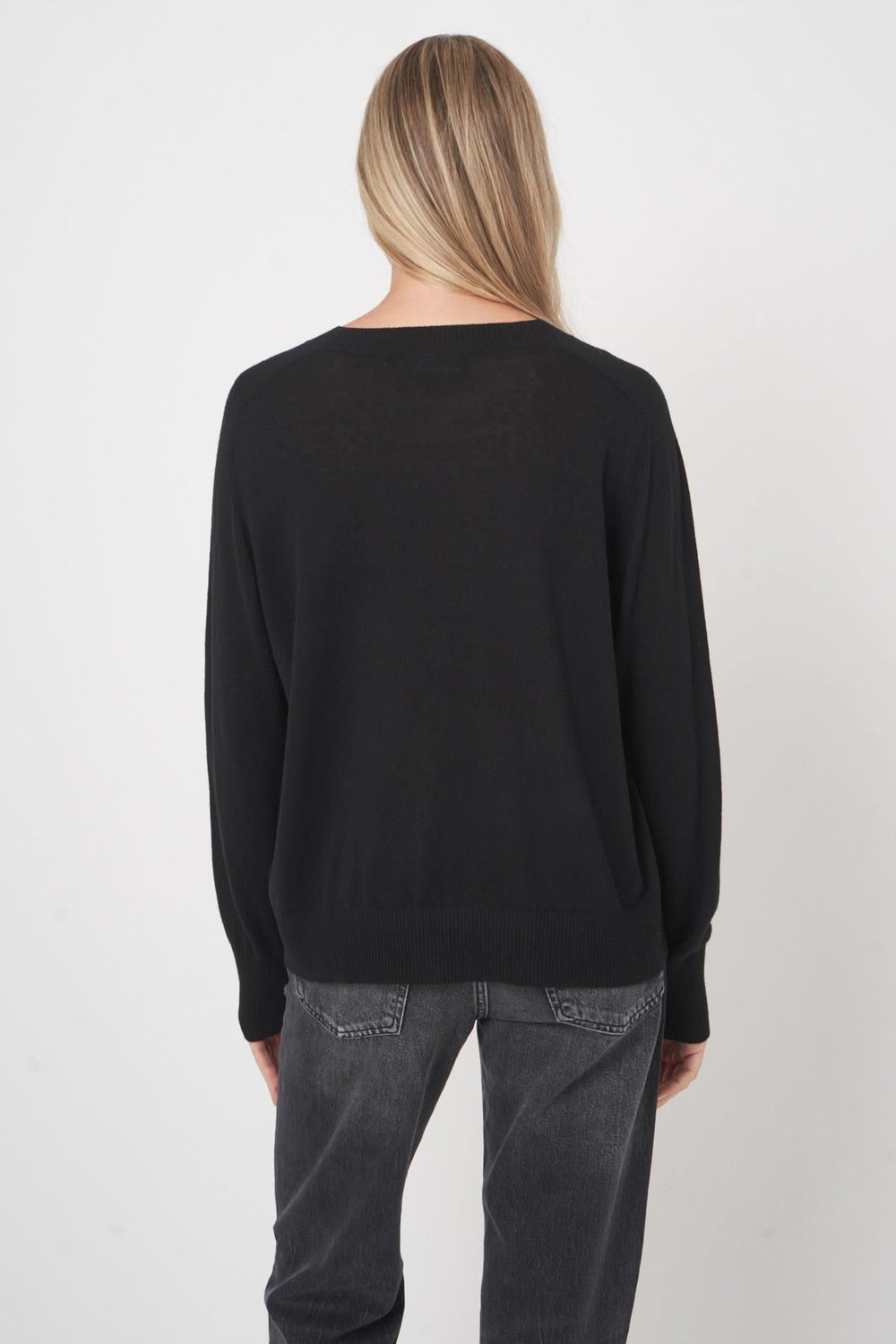 Chandail en laine noir, coupe droite, finition côtelée, porté avec un jean pour un style décontracté.