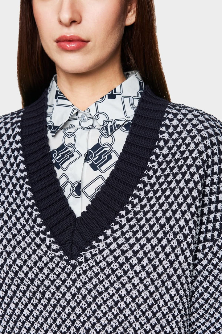 Pull court tricoté en noir et blanc avec encolure en V porté sur une chemise à col.