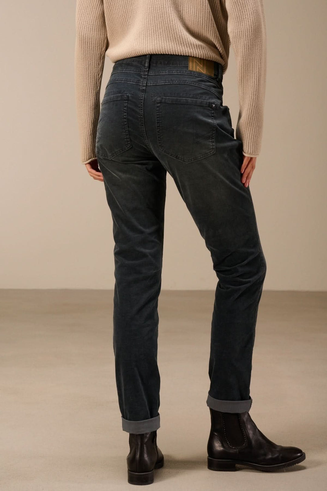 Pantalon en velours côtelé coupe ajustée pour un style moderne et confortable, porté avec un pull beige et des bottines noires.