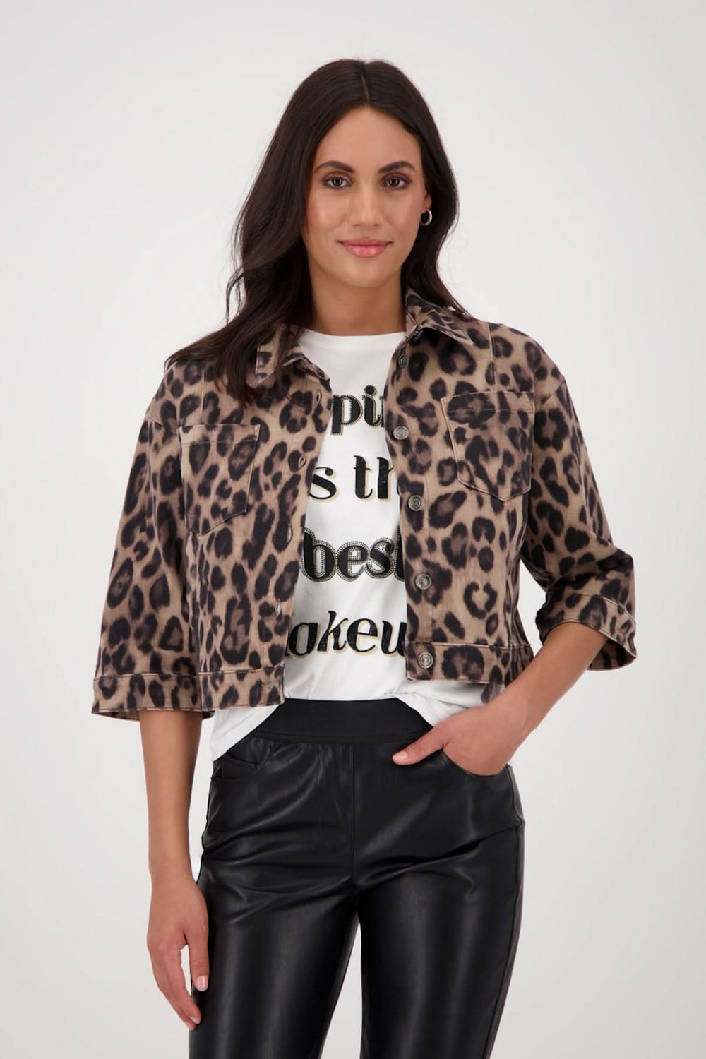 Veste courte à imprimé léopard avec manches 3/4, portée sur un t-shirt graphique et pantalon simili cuir.