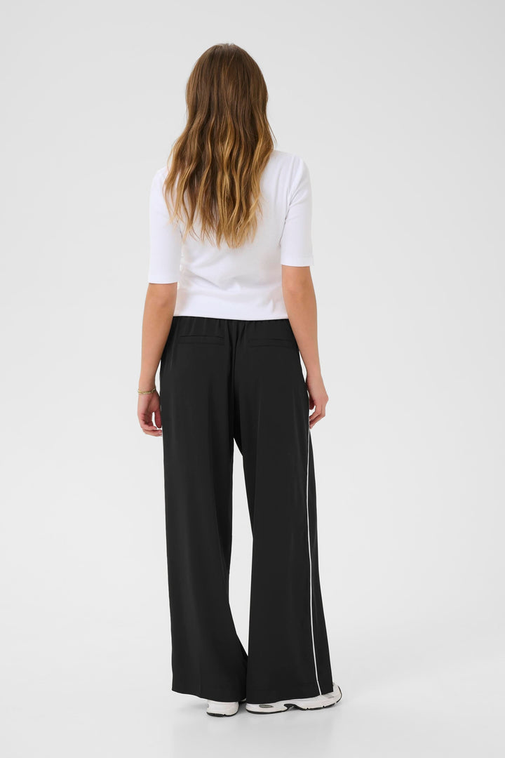 Femme vue de dos portant un pantalon Tessa fluide à jambe large avec un t-shirt blanc.