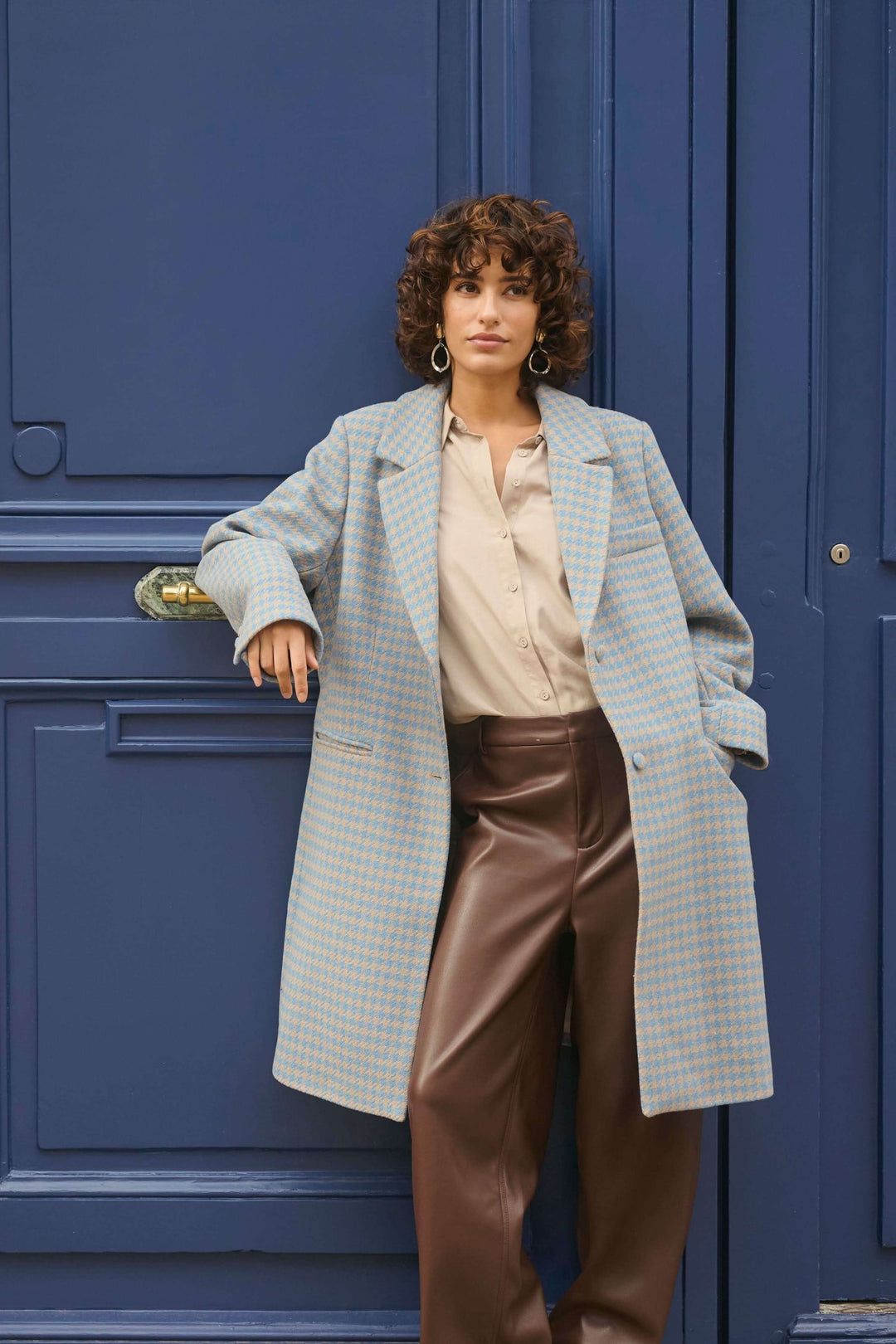 Femme portant Manteau Westie à motif pied-de-poule et coupe droite devant une porte bleue.