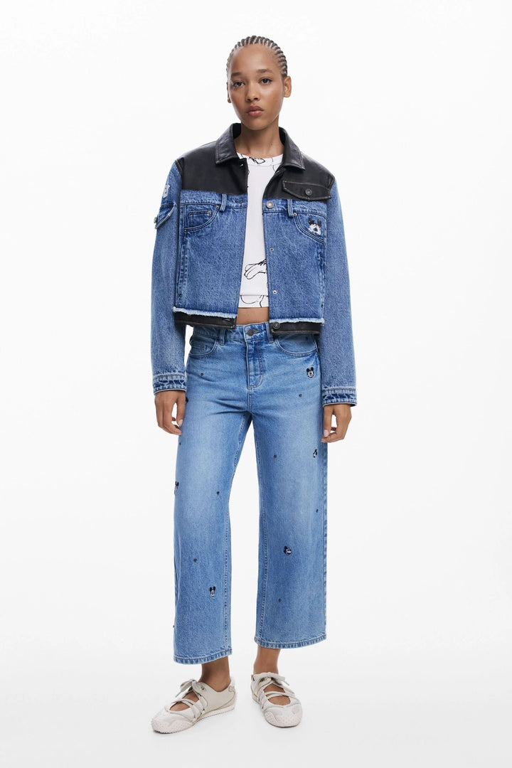 Jean à jambe large avec broderies Mickey Mouse, porté avec une veste en denim et un t-shirt graphique.